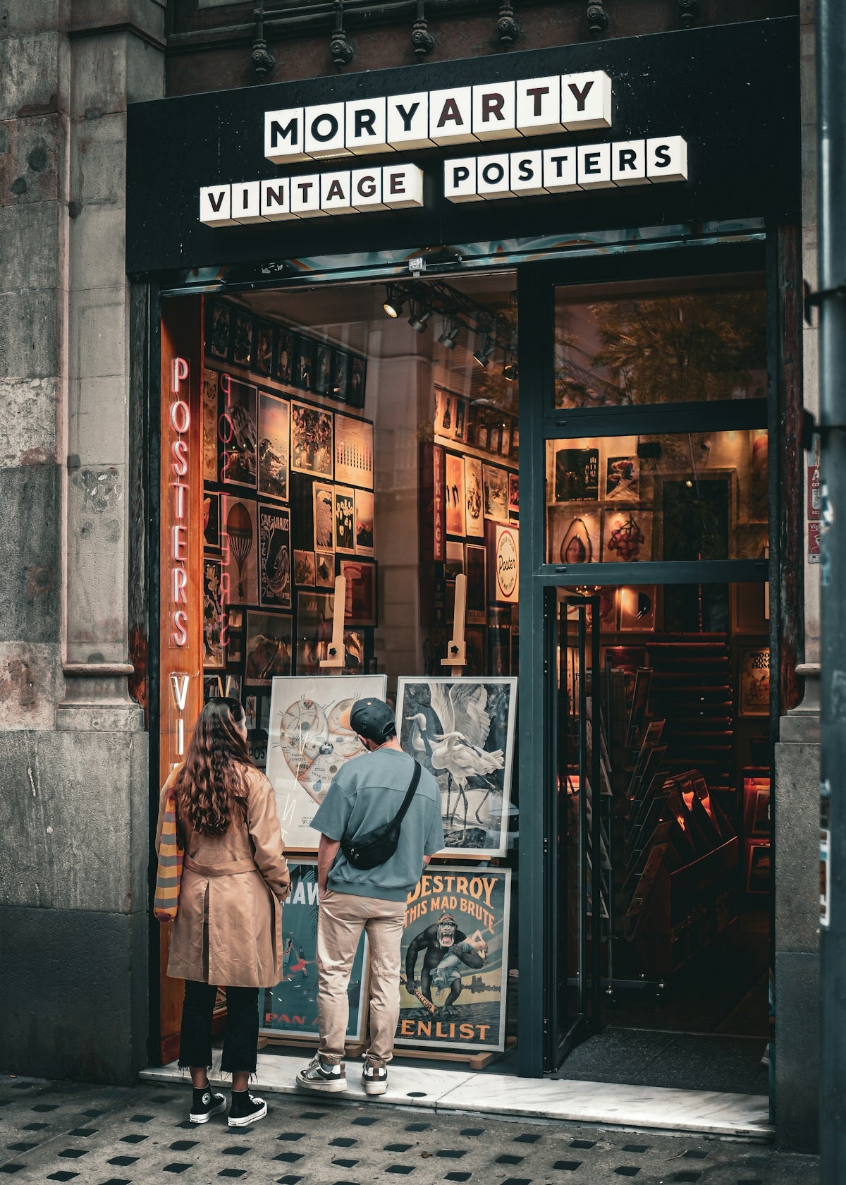People looking at vintage posters in a shop window.